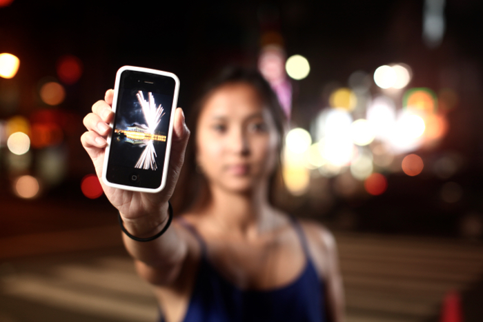 a girl holding up an iPhone outdoors at night